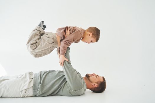 Paternity lifestyle. Father lifting child on white background. Dad and child smile and having fun together