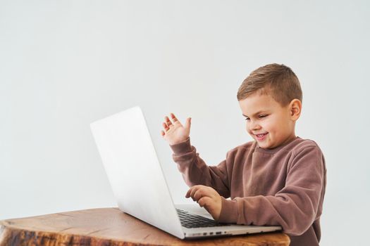 Emotional child with laptop talking with friends online. Handsome kid typing text on laptop and smile
