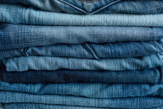 Stack of a stack of old jeans various shades of blue jeans. Denim jeans texture. Denim background texture for design. Canvas denim texture. Blue denim background.