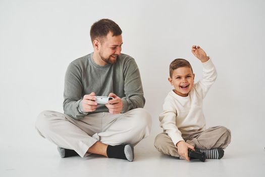 Paternity. Father and son play gamepad console game laugh and have fun together. Gamers play computer games