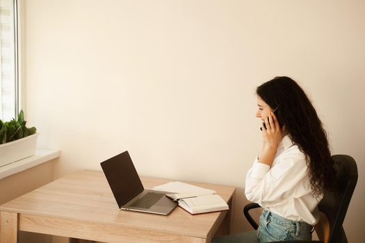 Business woman with laptop working online at freelance work. Attractive girl watching online video tutorial about designer work.