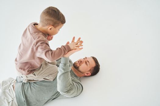 Father and son have fun and fool around together on white background. Child laughs with dad. Fatherhood. Child care