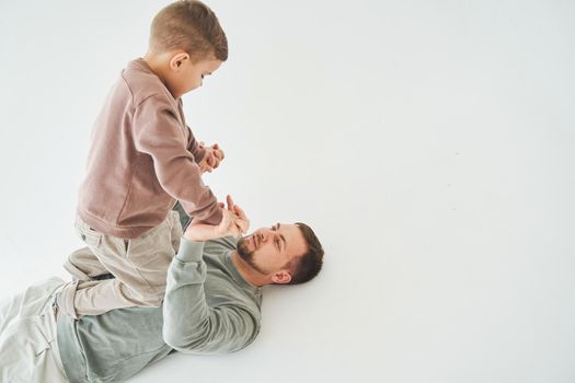 Father and son have fun and fool around together on white background. Child laughs with dad. Fatherhood. Child care