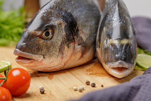 Fresh dorado fish, on a wooden board, two heads close-up.