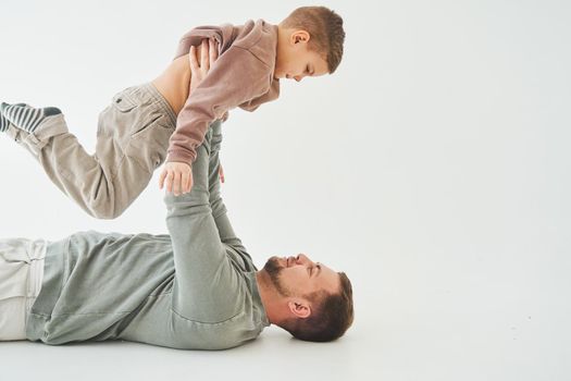 Father raises his son and plays with him, have fun and spend time together. Paternity. Handsome son in his fathers arms