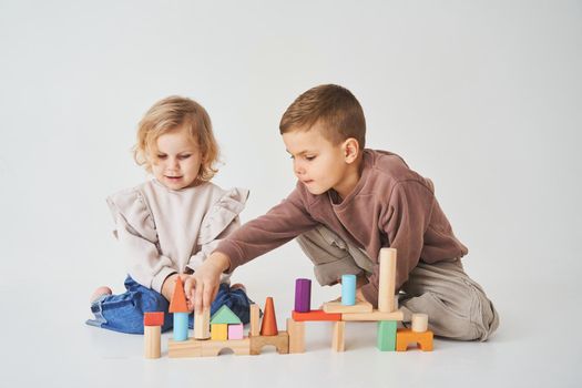 Boy and girl smiling, having fun and playing colored bricks toy on white background. Children have smiling and have fun together