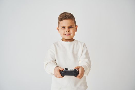 Emotional child with gamepad on white background. Boy is playing games