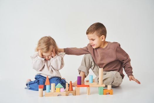 Boy and girl smiling, having fun and playing colored bricks toy on white background. Children have smiling and have fun together