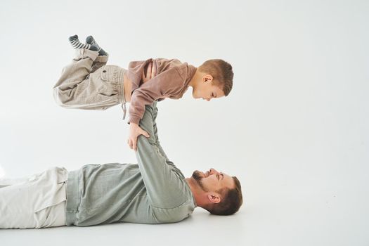 Paternity lifestyle. Father lifting child on white background. Dad and child smile and having fun together