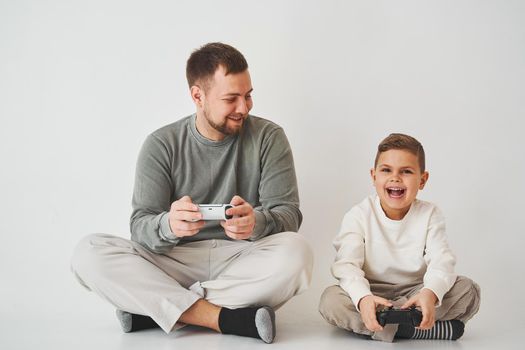 Son and dad play console games with gamepad. Boy and his father spend time togerher and playing computer games