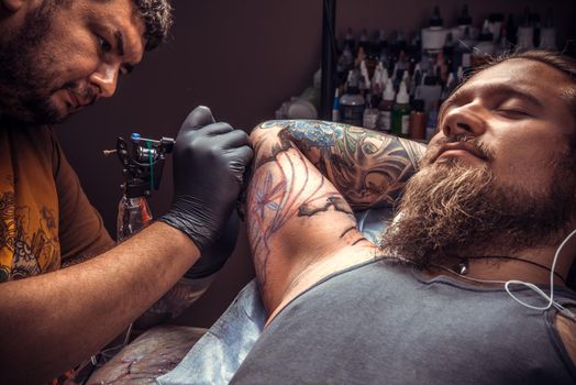 Tattoo artist makes tattoo pictures in tattoo studio./Master at work in tattoo studio.