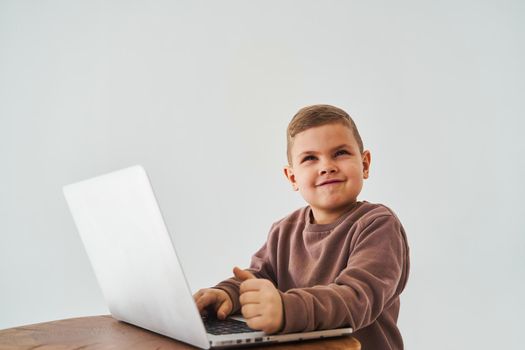 Child boy study online with laptop and smiles. Online education and e-learning. Child taking online courses on laptop