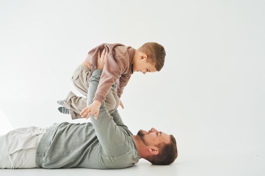 Paternity lifestyle. Father lifting child on white background. Dad and child smile and having fun together