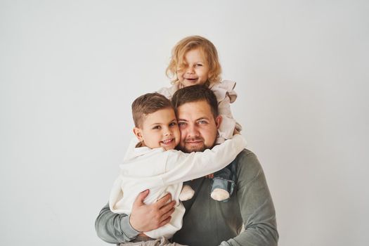 Happy family. Father, daughter and son hugging and smiling on white background. Paternity. Single father bring up his children