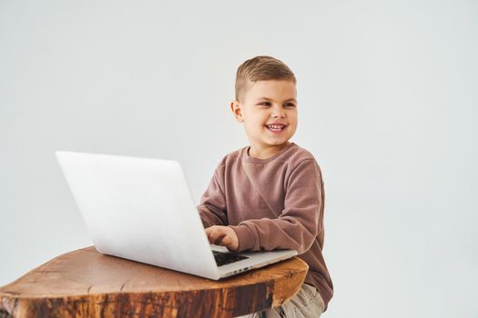 Gambling addiction. Handsome kid gamer is gaming on laptop on white background. Emotional child play online games on laptop