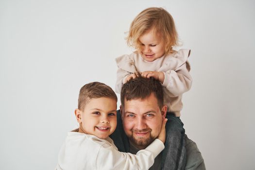 Close-up portrait of father, son and daughter. Happy family hugging and smiling on white background. Paternity. Single father bring up his children