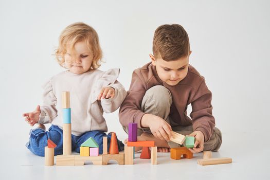 Boy and baby girl smiling, having fun and playing colored bricks toy on white background. Children have smiling and have fun together