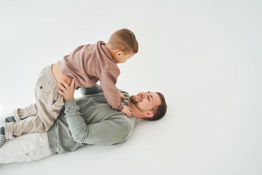Father raises his son and plays with him, have fun and spend time together. Paternity. Handsome son in his fathers arms