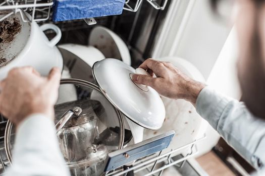 young man pulls the dishes out of the dishwasher . photo with copy space