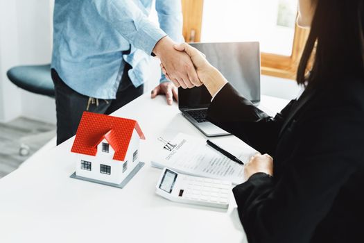 Laws, contracts, mortgages, clients join hands with real estate agents congratulating real estate agents on home and land purchase agreements with insurance to reduce risks during home installments.