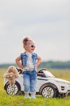 girl in sunglasses stands near the car in nature