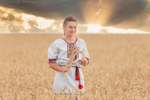 girl in an embroidered shirt on a wheat field and a sunset sky