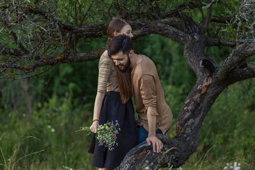 young couple hugging near a tree