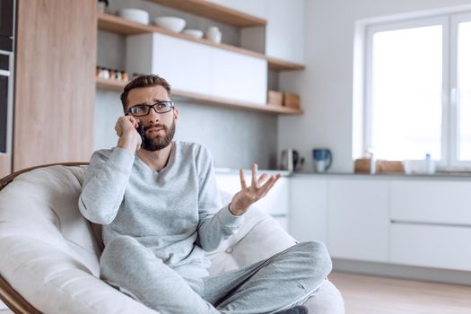 cheerful man talking on a mobile phone sitting in a comfortable chair. photo with copy space