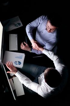 top view .handshake colleagues sitting at the Desk.the concept of overtime work