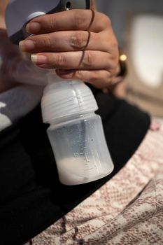 Young mother using an electric breast pump pumping breast milk for her baby.