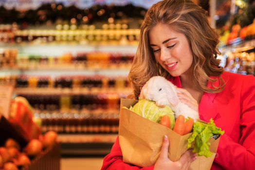 The young pretty woman is shopping to buy vegetables for her pet white rabbit at the supermarket