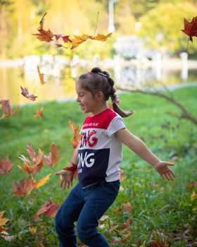 The girl throws colorful maple leaves for a walk in the park. Russia Moscow September 24, 2020