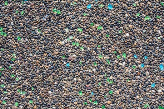 texture of concrete wall covered with shards of multicolored bottle glass