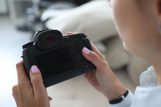 Close-up of woman photographer go through pics on camera backstage after photoshot. Professional photographer, black device screen. Mockup, art concept