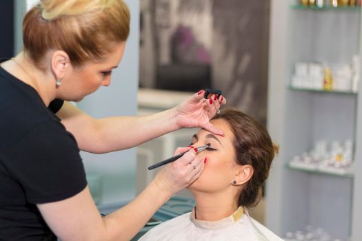 Master stylist makes eye makeup for a girl in a beauty salon. Russia Moscow August 20, 2020.