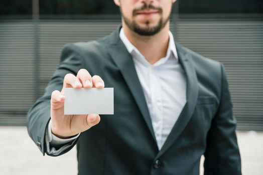 close up businessman standing outdoors showing blank white business card