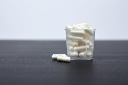 transparent glass filled with medicine pills on white black background, side view