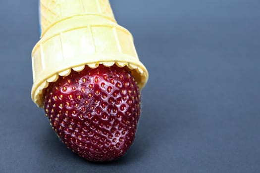 Straberrry in waffle cone - healthy dessert concept on black background