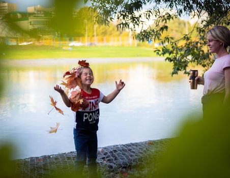 The girl throws colorful maple leaves for a walk in the park. Russia Moscow September 24, 2020