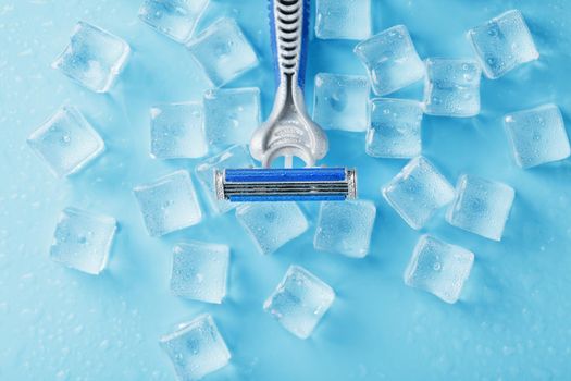 Shaving machine on a blue background with ice cubes. The concept of cleanliness and frosty freshness