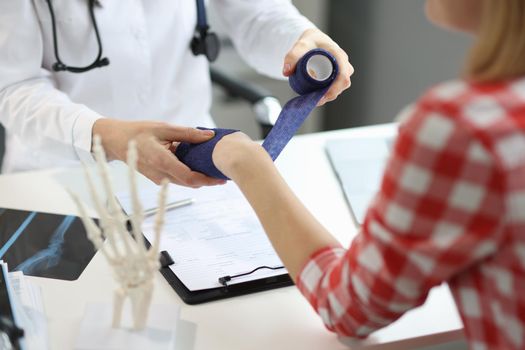 Close-up of physiotherapist man put bandage on female patient hand, post traumatic rehabilitation. Medicine, healthcare, recovery, hospital help concept