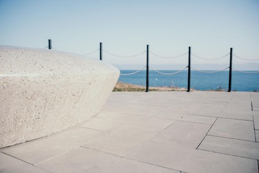 Sea side public park with concreate bench in spring evening.