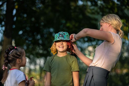 Mom plays with children in the park, puts leaves under her hat. Russia Moscow September 24, 2020.
