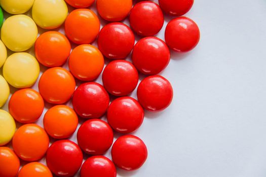 Rainbow of multicolored sweet candy dragees on isolated white background. Decorative Creative composition of round candy dragees in Rainbow colors. Concept Summer. Top view. Flat lay.