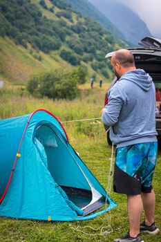 A company of friends is resting in the mountains, setting up a tent. Mountains of the Caucasus. Russia Ossetia Vladikavkaz August 15, 2020.