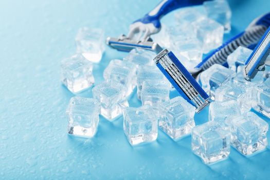 Shaving machine on a blue background with ice cubes. The concept of cleanliness and frosty freshness