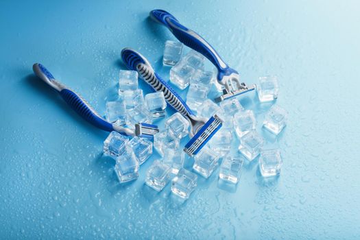 Shaving machine on a blue background with ice cubes. The concept of cleanliness and frosty freshness