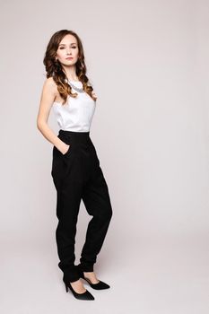 Front view of elegant successful female wearing smart outfit and glasses and posing on isolated background. Intelligent woman with folded arms looking at camera in studio. Concept of job and business.