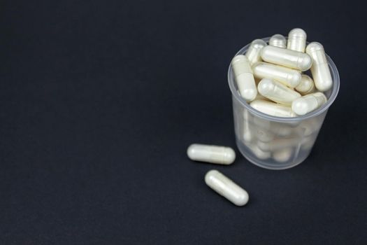 transparent glass filled with medicine pills on white black background, side view