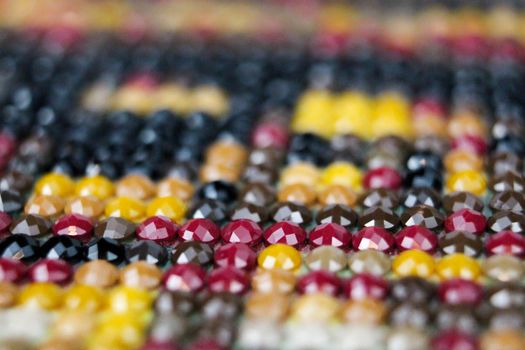 Closeup on colorful mix of round drill beads for diamond painting. Multicolored rainbow of shiny beads for background art. Macro of diamand painting.